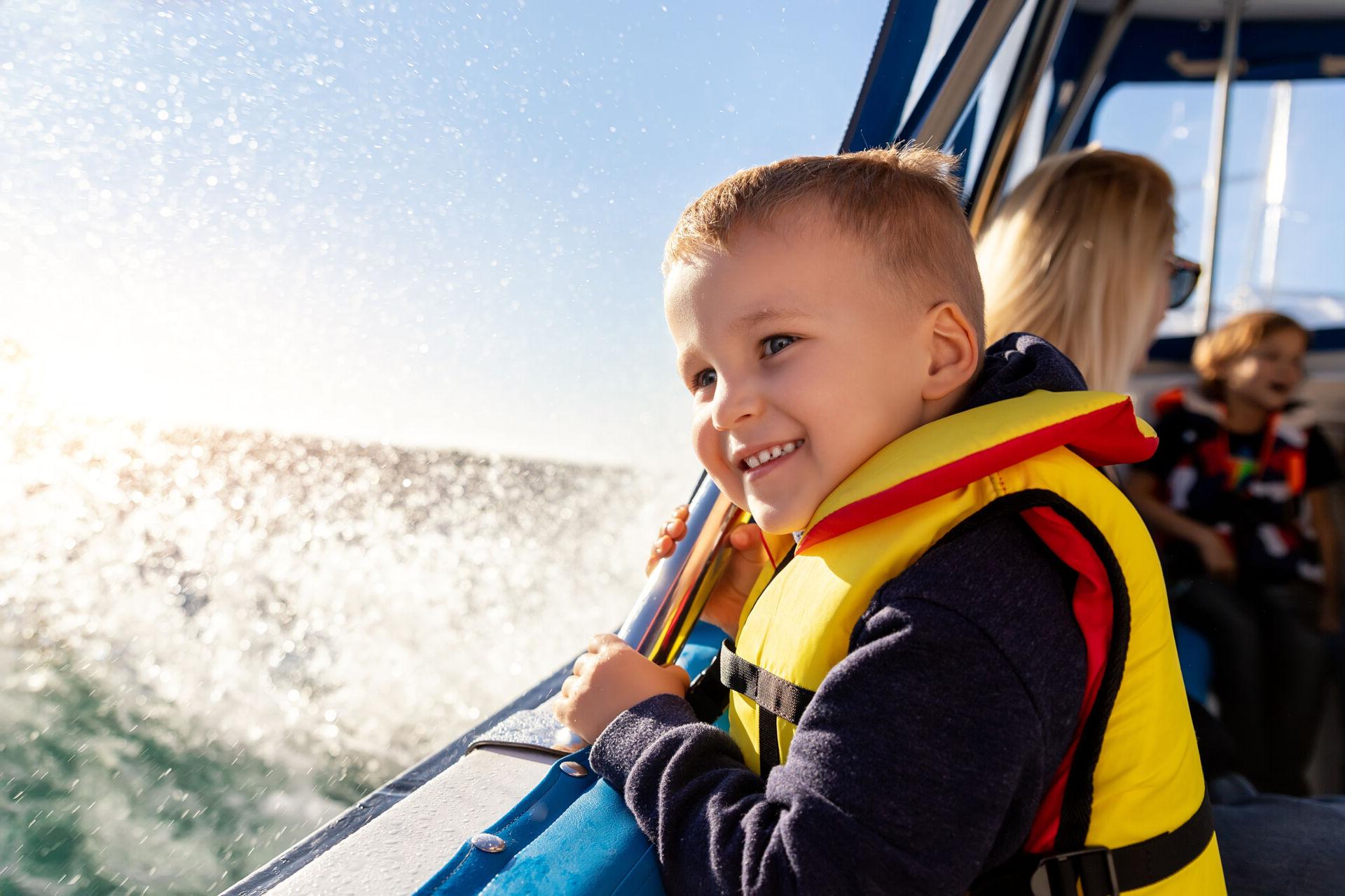 A little kid is smiling as he and his family have fun on their new boat.